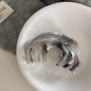 Detailed view of the large marble ink pattern hair claw clip on a white ceramic plate