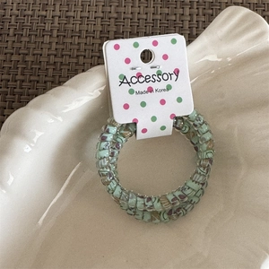 Detail view of a green floral spiral hair tie inside a white shell-shaped dish