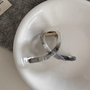 Detail of large ink-style marble hair claw with gold spring on a ceramic bowl