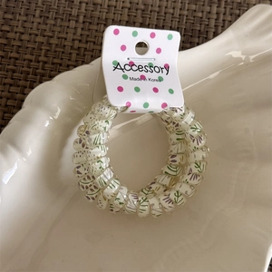 Close-up of floral spiral hair tie on shell-shaped ceramic plate and woven mat
