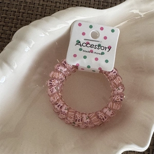 Detailed view of pink floral spiral hair tie on a white shell tray with woven background
