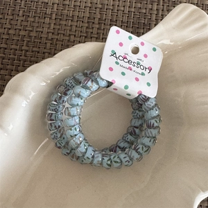 Detailed shot of light blue floral spiral hair tie on a white shell plate