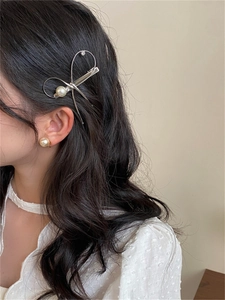 Détail d'une pince à cheveux nœud argenté avec perle sur modèle pour un style élégant