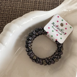 Detail of a high-elastic spiral phone cord hair tie with floral patterns on a tray