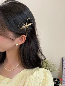 Pince à cheveux noeud doré avec perles et parure de bijoux assortie sur un mannequin