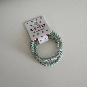 Detailed macro of green polka dot spiral hair ties in 3-piece set with card packaging
