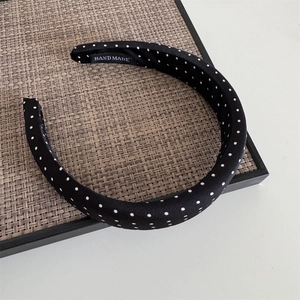 Detailed close-up of a handmade black and white polka dot headband with sponge padding