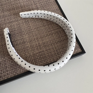Detailed view of a vintage padded headband with black and white polka dots on a texture board