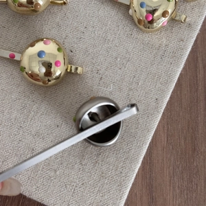 Detailed close-up showing the metallic spring clip mechanism of the colorful polka dot hairpin