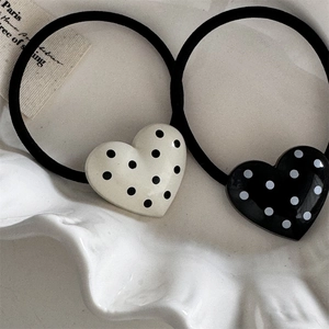Macro shot of black and white heart polka dot hair ties on a white ceramic tray