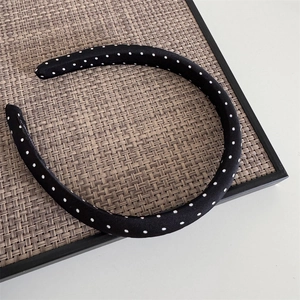 Detail of a vintage black polka dot headband on a rustic woven tray for hair styling