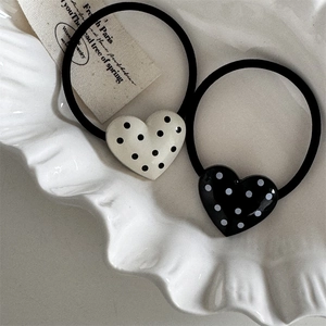 Close-up of vintage heart-shaped polka dot hair ties on a white ceramic plate decoration