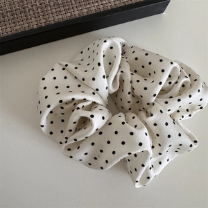 Detailed close-up of a polka dot scrunchie with soft pleated texture and high-quality fabric