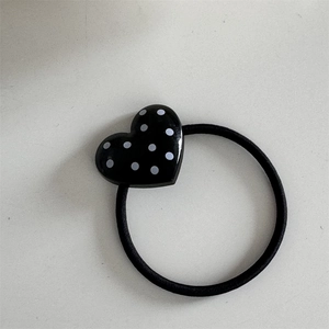 Detailed view of elastic hair tie with heart-shaped black and white polka dot ornament