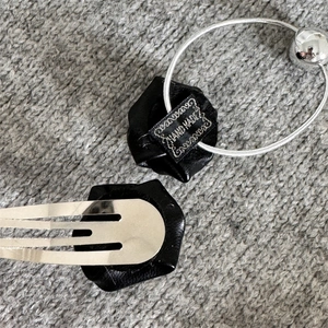 Detailed view of black leather rose hair clip and tie with silver metal hardware accents