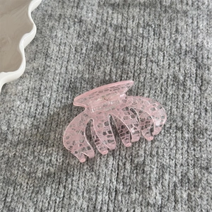 Détail macro d'une pince à cheveux rose avec motif dentelle blanc sur résine fine