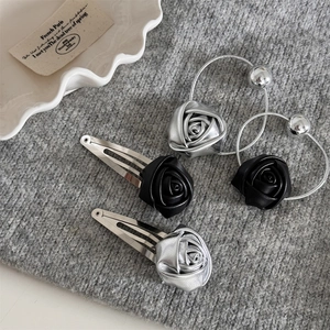 Detailed set of leather rose hair clips and metallic silver elastics on grey texture