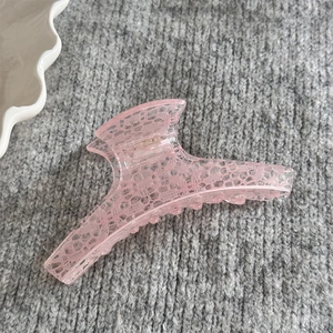 Détail de la pince à cheveux en acrylique rose avec motif de dentelle élégant