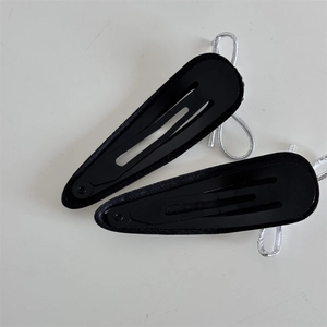 Detail of black teardrop snap hair clips with silver fabric wrap and woven accents