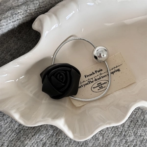 Detail of a chic black leather rose hair clip with a silver metallic sphere on shell tray