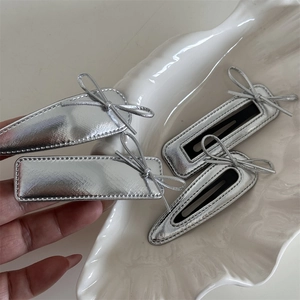 Detail of silver metallic leather bow hair clips in rectangular and teardrop shapes
