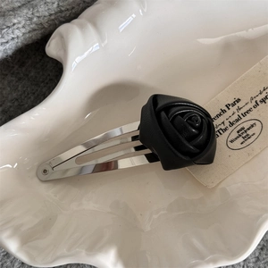 Detail of a vintage silver metal BB hair clip featuring a black leather rose ornament