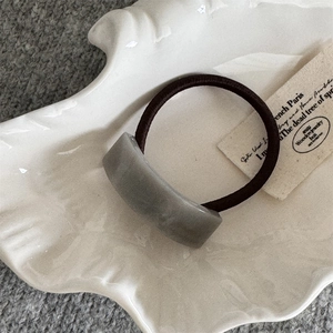 Détail de l'accessoire en résine grise courbée sur élastique pour queue de cheval chic