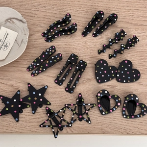 Close-up of black hair clips with colorful polka dots in star and heart shapes
