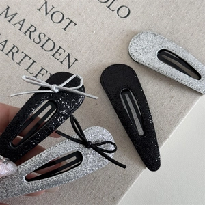 Macro shot of silver glitter hair clips with bow detail on a textured canvas backdrop