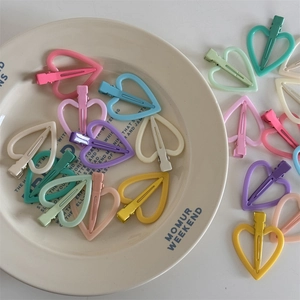Macaron hartvormige haarspelden in diverse pastelkleuren op een stijlvol keramisch bord