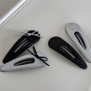 Glittery silver and black BB hair clips set with ribbon bows on textured background