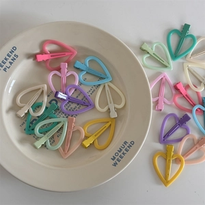 Close-up van matte holle hartvormige haarspeldjes in diverse pastelkleuren op een bordje