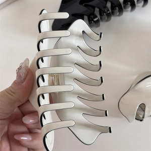 Detail view of black and white large hair claws with metal spring and smooth finish