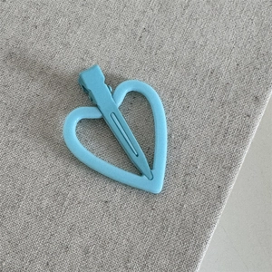 Gedetailleerde weergave van lichtblauwe hartvormige haarklem met matte textuur en metalen clip