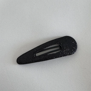 Detailed macro view of black drop hair clip with shimmering silver glitter finish