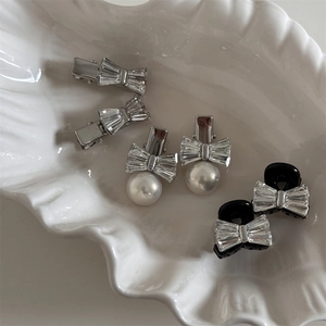 Détail de barrettes nœuds en strass brillants et perles dans un plat blanc en céramique