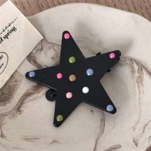 Macro shot of a black star-shaped hair clip featuring colorful polka dots and matte finish