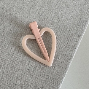 Detail van roze mat hartvormige haarklem met hol frame-ontwerp op linnen stof