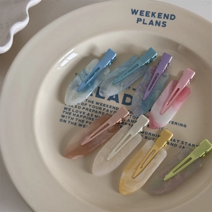 Detailed close-up of 8 marble texture acetate hair clips in various colors in a ceramic dish