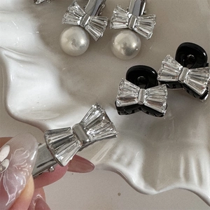Barrettes à nœud en strass élégantes et pinces à bec de canard en perles sur plateau blanc