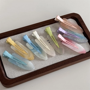 Close-up of eight colorful macaron resin hairpins with marble texture in a tray