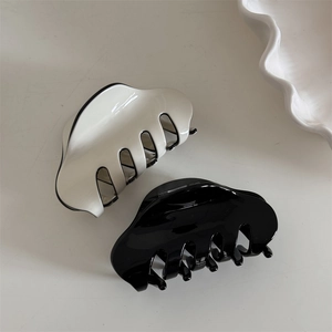Macro shot of black and cream glossy hair claws set on a minimalist background