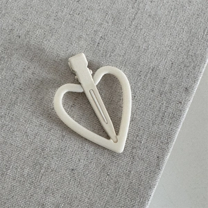 Detail van hartvormige haarklem met witte matte afwerking en metalen eendenbekclip