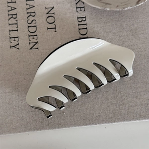 Close-up of cream white glossy French hair claw clip on soft textured fabric background