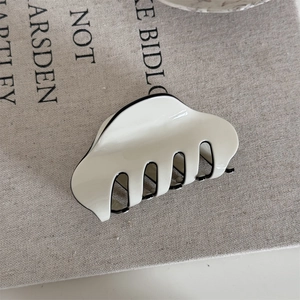 Detail of cream shark hair claw with black trim on linen background in French style