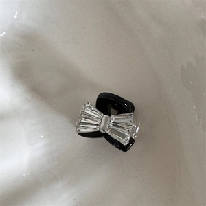 Détail d'une mini pince à cheveux avec nœud en strass brillant sur base noire