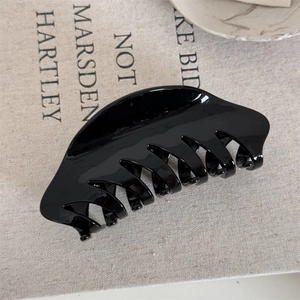 Close-up of sleek black acrylic French hair claw with strong glossy finish and fine teeth
