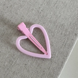 Detailopname van een roze hartvormige haarklem met bijpassende metalen clip
