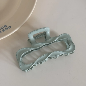 Detail view of light green hair claw clip with faux leather texture and stitch patterns