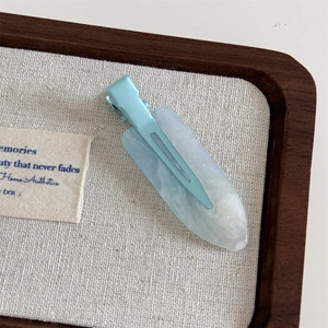 Detail of light blue marbled hair clip with subtle glitter finish on a display tray